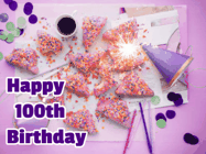 Happy Birthday Age 100 GIF, 100th Birthday GIF: A big paper sparkle highlights this animated birthday gif showing a birthday cake place setting with decorations.