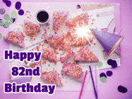 Happy Birthday Age 82 GIF, 82nd Birthday GIF: A big paper sparkle highlights this animated birthday gif showing a birthday cake place setting with decorations.