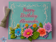 Happy Birthday Alexander GIF: Animated Birthday GIF as a colorful birthday card reading Happy Birthday Name and flower petals floating past.