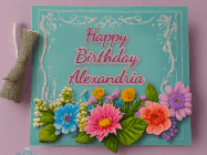 Happy Birthday Alexandria GIF: Animated Birthday GIF as a colorful birthday card reading Happy Birthday Name and flower petals floating past.
