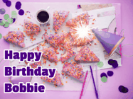 Happy Birthday Bobbie GIF: A big paper sparkle highlights this animated birthday gif showing a birthday cake place setting with decorations.
