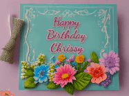 Happy Birthday Chrissy GIF: Animated Birthday GIF as a colorful birthday card reading Happy Birthday Name and flower petals floating past.
