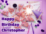 Happy Birthday Christopher GIF: A big paper sparkle highlights this animated birthday gif showing a birthday cake place setting with decorations.