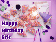 Happy Birthday Eric GIF: A big paper sparkle highlights this animated birthday gif showing a birthday cake place setting with decorations.