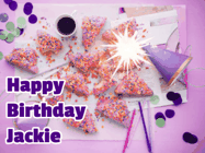 Happy Birthday Jackie GIF: A big paper sparkle highlights this animated birthday gif showing a birthday cake place setting with decorations.