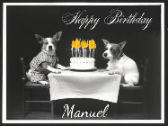 Happy Birthday Manuel GIF: Vintage animated birthday card gif with name, flickering candles, birthday cake, and 2 dogs sitting at the table.