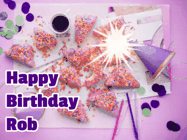 Happy Birthday Rob GIF: A big paper sparkle highlights this animated birthday gif showing a birthday cake place setting with decorations.