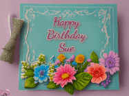Happy Birthday Sue GIF: Animated Birthday GIF as a colorful birthday card reading Happy Birthday Name and flower petals floating past.